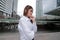 Wide angel shot of confident young Asian woman with white shirt at urban building public background.