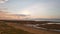 Wide angle aerial view above sandy beach of pastel sunset cloudscape over the sea