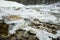 Wide angle close up of river in winter. Flowing water and stones covered with ice and snow