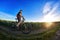 Wide angle of the cyclist standing on the trail on the field against beautiful landscape.