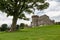 The wide-angle landscape shot of ancient Balloch Castle and a tree in Scotland, UK which was built on a hill in an early 19th