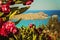 A wide angle landscape view of beautiful Aegean ocean in Greece, Rhodes with red flowers on a foreground and sail boats on the bay