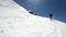 A wide angle male skier aged in black equipment and white helmet with ski poles rides on a snowy slope on a sunny day