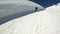 A wide angle male skier aged in black equipment and white helmet with ski poles rides on a snowy slope on a sunny day