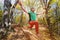 Wide angle male tightrope yogi balances on one leg in heron pose barefoot on slackline in autumn forest. The concept of