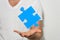 Wide angle shot of a blue piece of jigsaw puzzle over a person\'s fingers