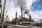 wide-angle shot of busy petrochemical plant, with smoke and steam rising from various buildings