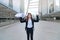 Wide angle shot of cheerful young Asian business woman raising paperwork or charts in her hands at urban building city background.