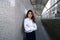 Wide angle shot of confident young Asian businesswoman standing and positive look at walkway in the urban building background. Le