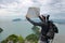 Wide angle shot of hipster young Asian man with backpack standing on the stone and exploring map on the mountain