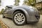 Wide angle shot of modern silver car parked on paved sunny quiet suburban street on sunny day. Transportation, comfort, speed