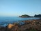 Wide angle shot of the ocean surrounded by mountains and twigs growing on them