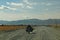 Wide angle shot of a person on a motorcycle on the road behind the mountains