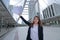 Wide angle shot of successful young Asian businesswoman raising hands and showing charts or graphs at urban building background.