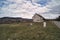 Wide angle shot of a vintage a shaped wooden house in the middle of nowhere. Countryside view of a home against dramatic clouds