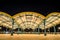 Wide angle shot of a yellow roof supported by green arches and columns at night