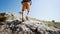 Wide angle slow motion feet young adult man hiker walking up the rocky slope at summer day against blue sky