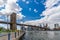 Wide angle view Brooklyn Bridge with lower Manhattan skyline, One World Trade Center Empire Fulton Ferry Park