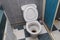 A wide angle view photo of a sitting type lavatory in a toilet with shower cubicle and checkered floor tiles