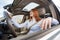 Wide angle view of young redhead woman driver fastened by seatbelt driving a car smiling happily