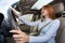 Wide angle view of young redhead woman driver fastened by seatbelt driving a car smiling happily