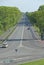 Wide asphalt road highway street with lanterns and trees on the sidelines