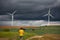 Wide back view shot of a young adult man walking through a sustainable Windmills Field Of Valdorros Town, Burgos, Spain.