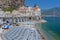 Wide beach covered with white blue umbrellas in historical village of Atrani, Amalfi Coast, Italy
