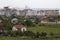 Wide beautiful summer panorama of quiet suburban area with nice comfortable cottages and green gardens on background of modern dev