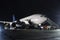 Wide-body passenger aircraft with air-stairs at the night airport apron. Airplane ground handling