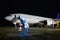 Wide body passenger aircraft with boarding ramp at the night airport apron. Airplane ground handling