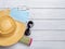 Wide brim straw hat on a rolled up beach mat, sunglasses, medical face mask and hand sanitizer on a white wood desk. Protection