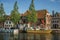 Wide canal with brick houses, boats moored on its bank reflected in water and blue sky of sunset in Weesp.
