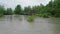 Wide dirty river with muddy water on the road and bridge across the river in the village in flooding period during heavy