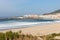 Wide empty beach with beautiful waves and white town on background. Vila Praia de Ancora, Portugal, landmark.