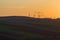 Wide evening panorama of dark plowed and green fields and electrical power line stretching to horizon on beautiful bright yellow