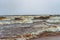 Wide expanse of winter waves with foam of a lake under the snowfall