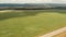 Wide green field with clouds shadows against hilly landscape