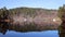 Wide lakeshore panorama with lodges of boat and woods in Scandinavia. Blue sky and evergreen woods reflection in the water in autu