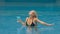 The wide middle shot pretty woman drinking blue cocktail alcohol liquor in swimming pool at hotel. Portrait of sexy girl