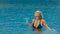 The wide middle shot pretty woman drinking blue cocktail alcohol liquor in swimming pool at hotel. Portrait of sexy girl