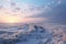 A wide open frost prairie bathed in rays of setting sun. Endless snow-covered steppe, dry plants sticking out from under the snow