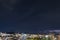 A wide open shot of a night city with dark blue sky and electric storm