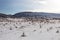 Wide open snow covered field with mountain range in distance on clear day