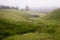 Wide panorama of beautiful foggy meadow. Dense fog over a stream in a meadow and trees silhouettes at early autumn morning