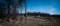 Wide panorama of burnt pine tree forest and logging machines