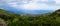 Wide panorama of the island of Crete with views of the ocean, coast, cloudy sky and green fields