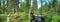 A wide panorama of the taiga wooden footpath along the mixed green along the river which reflects the blue sky. Paanayarvi