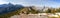 Wide Panoramic Landscape View of Exshaw Mountain Ridge, Green Meadows and Distant Snowcapped Canadian Rockies Peaks on a sunny Spr