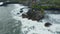 Wide panoramic view of Tanah Lot temple in dangerous sea. Strong ocean waves crashing into rocks around famous tourist